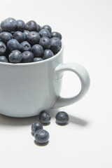 Blueberries on a white background on a large cup of ripe berries