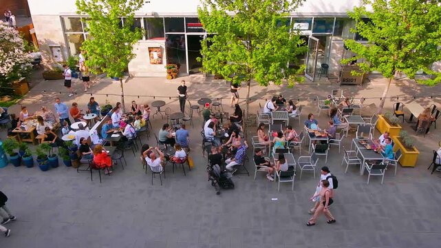 People eat at tables on the street, large companies sit on the terrace of a cafe or restaurant, a fashionable youth place, a view from above. Saint Petersburg, Russia - 23 June 2024