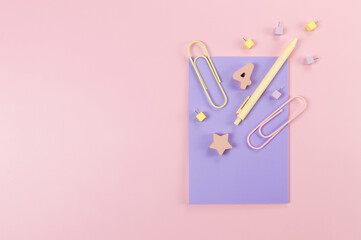 Top view of purple notebook on pink background. Paperclips, pen, number, shape and pins. School, office wallpaper. Flat lay, copy space.