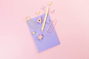 Top view of purple notebook on pink background. Paperclips, pen, number, shape and pins. School, office wallpaper. Flat lay, copy space.