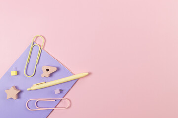 Top view of purple notebook on pink background. Paperclips, pen, number, shape and pins. School, office wallpaper. Flat lay, copy space.