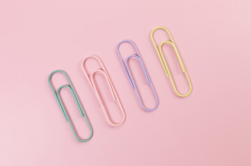 Top view of colorful paperclips on pink background. School, office wallpaper. Flat lay, copy space.