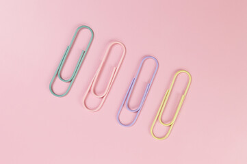 Top view of colorful paperclips on pink background. School, office wallpaper. Flat lay, copy space.
