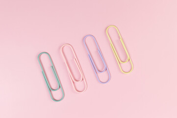 Top view of colorful paperclips on pink background. School, office wallpaper. Flat lay, copy space.