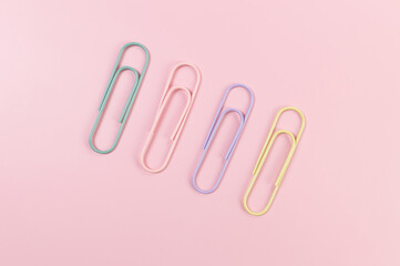 Top view of colorful paperclips on pink background. School, office wallpaper. Flat lay, copy space.
