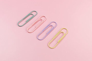 Top view of colorful paperclips on pink background. School, office wallpaper. Flat lay, copy space.