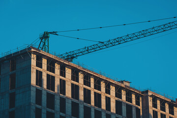 Fototapeta premium Building of the new high house by the crane. Industry new building business.