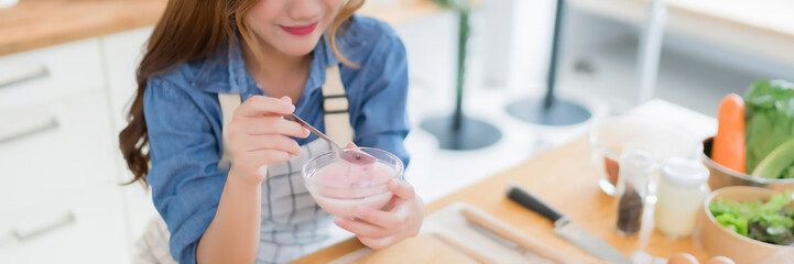 Young asian woman having breakfast to eating delicious yogurt with teaspoon after preparing fresh...