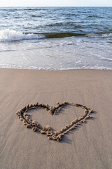 Heart drawn in the sand on the beach at sunset. Heart shape. Heart symbol. Love. Sea ​​foam.	