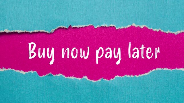Buy now pay later message writing on ripped torn blue paper on pink background