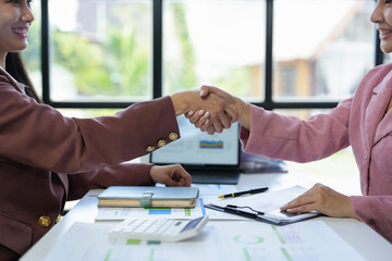 Two businesswoman shaking hands for success. Handshake. Collaboration, teamwork, friendship. Meeting of financial business partners, paperwork, calculations, investments, company partnerships.