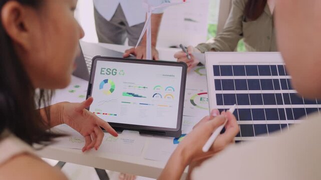 diversity team discussion focused on ESG (environment,social,governance)  focus on esg rating on laptop in a sustainable green office