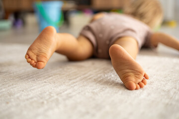 Close-up of baby feet, toddler lying on the floor at home,