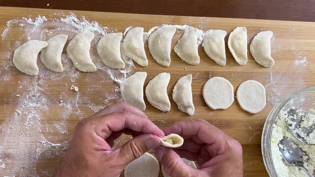 Cooking dumplings, empanadas, vareniki, perogies at home, the man prepares lunch.