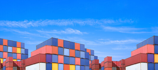 Group of many cargo containers stacked in terminal shipping yard area at commercial port against...
