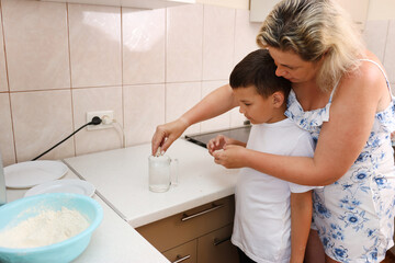 Mother and son prepare pizza dough. Cooking at home.