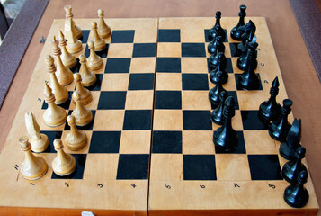 Wooden chess board with chess pieces close-up on a large table
