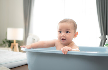 A tiny child enjoys taking a bath in a baby bathtub