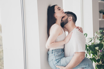 Photo of happy young couple move new place enjoy live together husband hold wife kiss neck new apartment room light house flat indoor