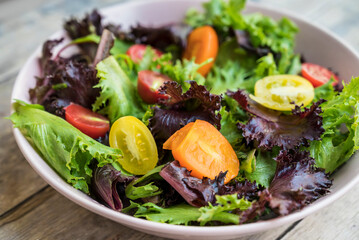 Mix of fresh green salad with red and yellow cherry tomatoes 