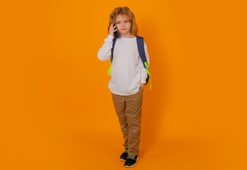 Studio full length body photo of school kid using mobile phone, tell, talk on the phone over yellow background.