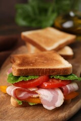 Tasty sandwich with bacon and tomato on table, closeup