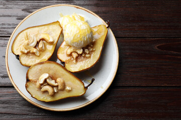 Delicious baked pears with nuts, ice cream and honey on wooden table, top view. Space for text