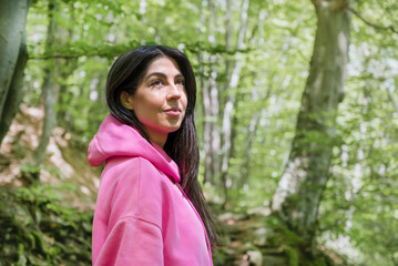 Naklejka premium Young woman standing in a green spring forest