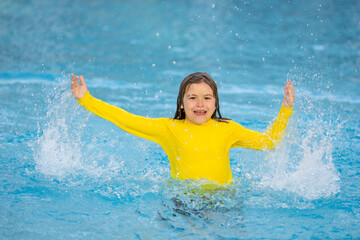 Excited child splashing water in pool. Little kid splashing in blue water of swimming pool. Cute boy swimming and splashing water with drops in pool. Child splashing and having fun in swim poolside.
