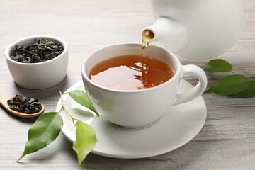 Pouring refreshing green tea into cup at grey wooden table, closeup