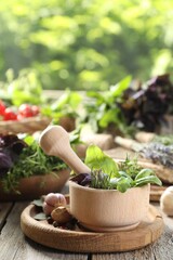 Different aromatic herbs, mortar with pestle and spices on wooden table, closeup