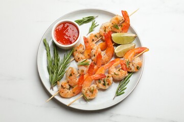 Skewers with delicious grilled shrimps served on white marble table, top view