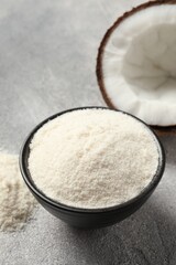 Coconut flour in bowl and fresh fruit on light grey table, closeup