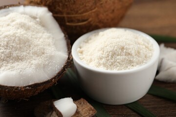 Coconut flour in bowl and fresh fruits on wooden table, closeup