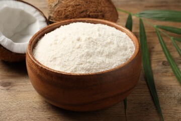 Coconut flour in bowl and fresh fruits on table, closeup