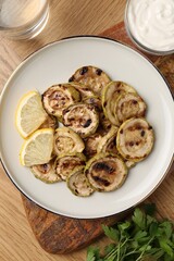 Tasty grilled courgette slices served on wooden table, flat lay