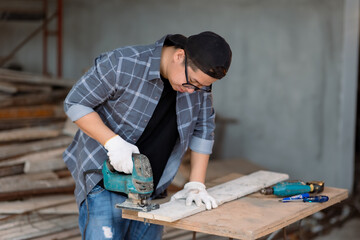 Carpenter asian man cutting wooden with handsaw at under construction home.