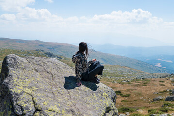 Traveler Woman sitting on a rock high in  the  summer mountain with amazing view .Vitosha Mountain ,Bulgaria 