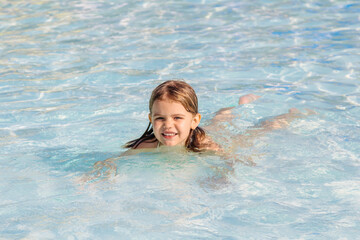 A little girl splashes happily in the pool on a sunny day. Bright colors capture the essence of summer fun and carefree moments. Ideal for family and children's materials.