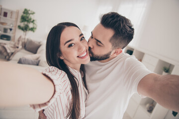 Photo of happy young couple move new place enjoy live together take selfie photo new kiss cheeks apartment room light house flat indoor