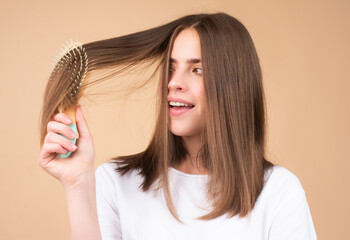 Portrait of charming brunette hair lady combing hair with hairbrush comb, isolated. Young beautiful...