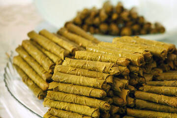 Homemade stuffed vine leaves are arranged in a row on the table,