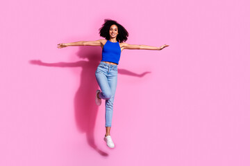 Photo of smiling girl jumping feel playful isolated pastel pink color background