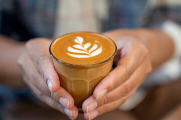 woman hand holding Hot coffee latte a cup of coffee cupucino with warm morning sunlight concept lifestyle before working , Start day by coffee