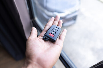 Close up of woman hand holds the car key isolated on a white Blurred background 