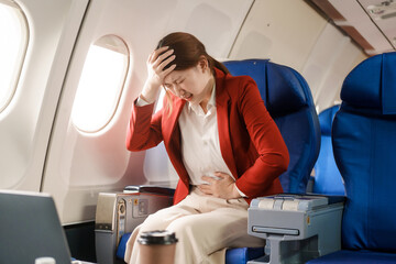 An Asian businesswoman travels abroad by plane,sitting near the window. She feels sick with air...