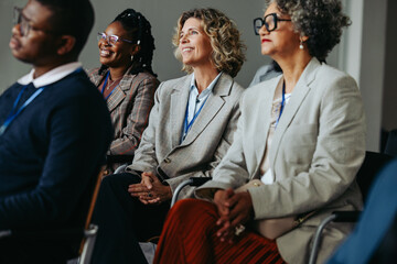 Mature businesswomen and coworkers attending a workshop presentation in conference audience