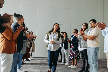 Group of employees clapping and smiling at a business conference, celebrating female achievements