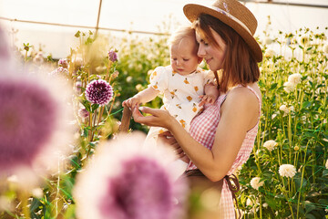 Looking at beautiful flowers. Mother and daughter are in the greenhouse