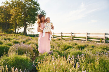 Holding baby in hands. Beautiful mother with her daughter on the farm